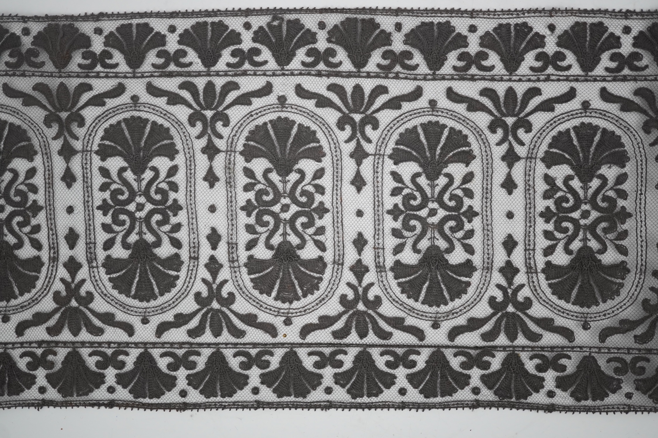 An unusual 19th century decorative length of charcoal grey machine furnishing lace, attributed to Christopher Dresser, together with a similar grey lace bonnet veil, both possibly Nottingham lace, furnishing lace 300cm j